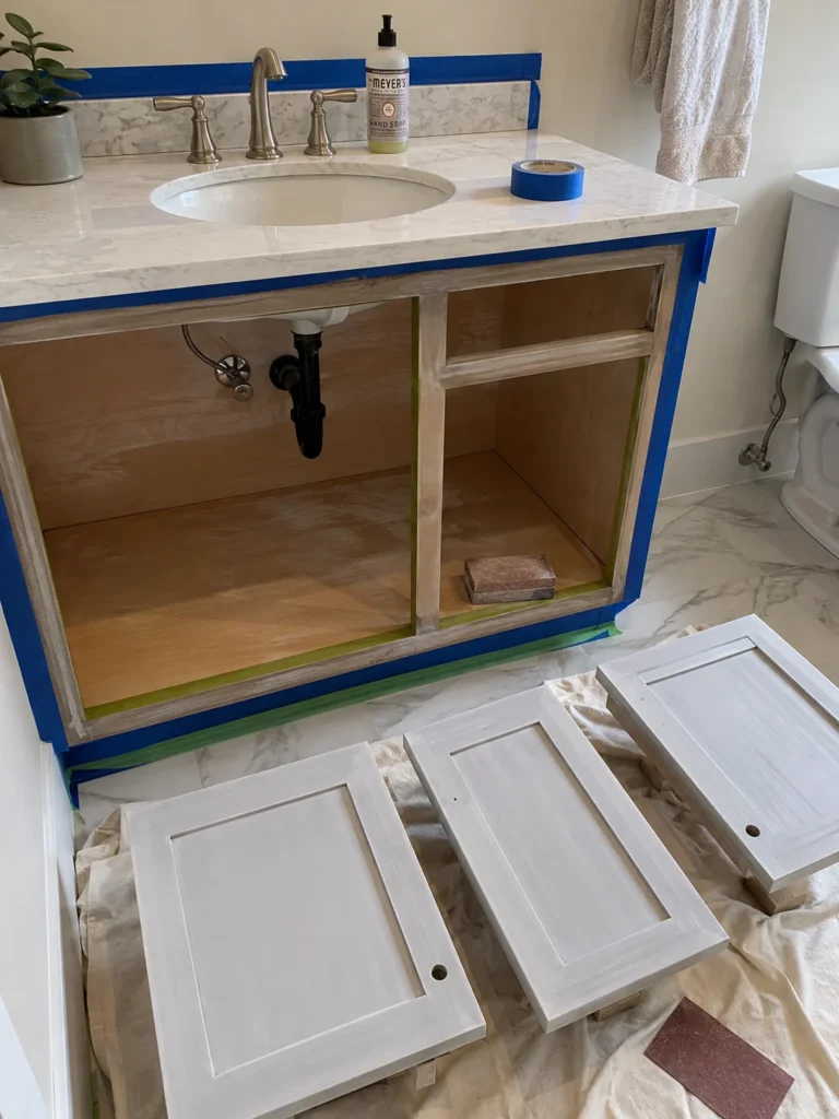 A small bathroom with a freshly painted vanity, updated cabinet hardware, and existing sink plumbing preserved.